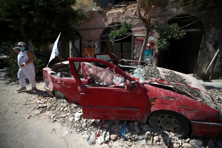 A woman walks past a damaged car following Tuesday's blast in Beirut's port area, Lebanon. REUTERS/Hannah McKay  
